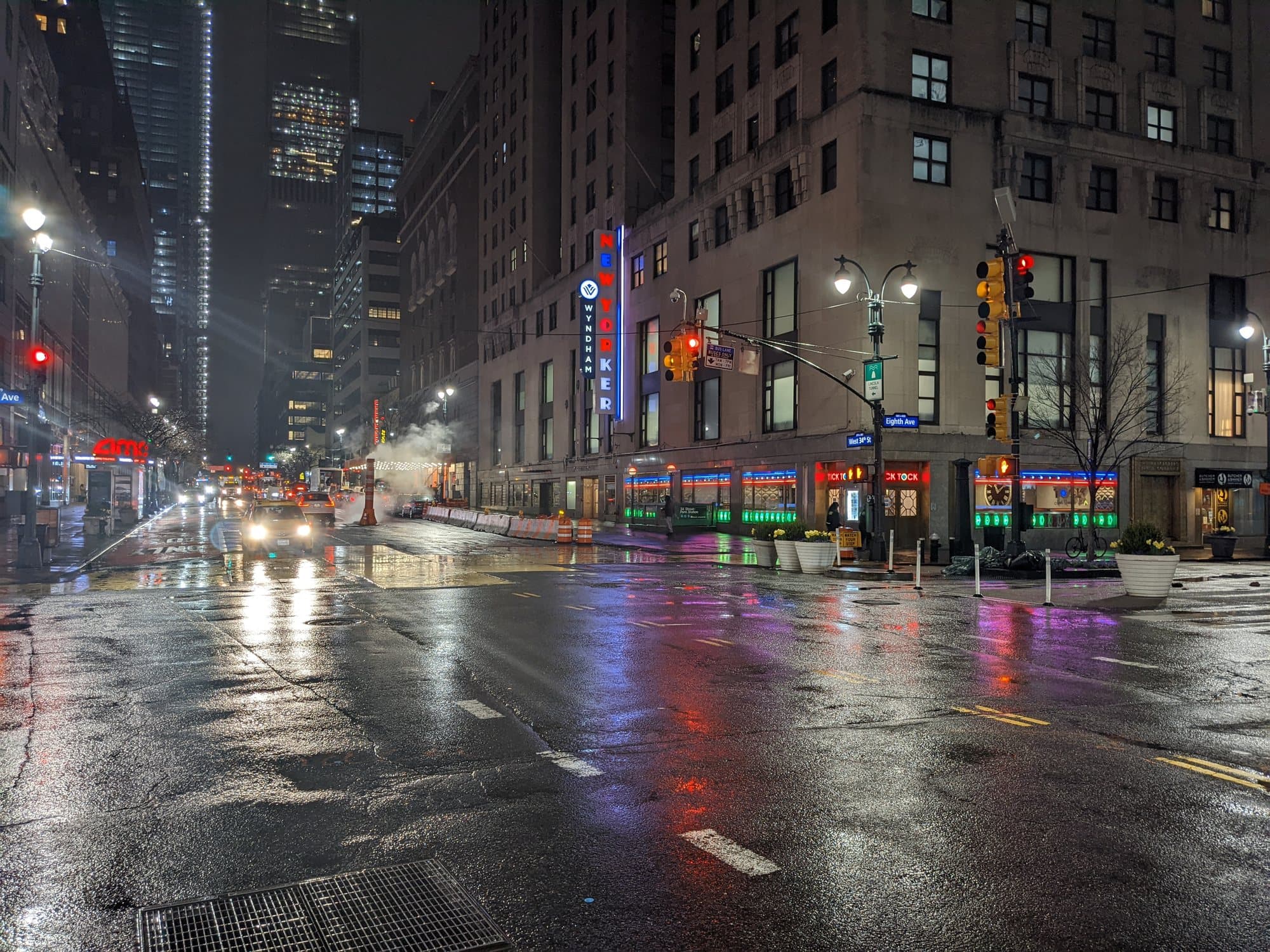 A rain-slicked Manhattan street at night, lit by traffic and neon