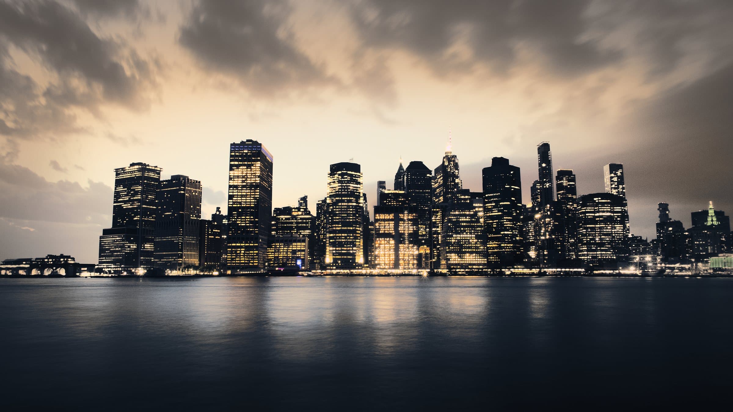 Manhattan skyline at dusk, silhouetted against a golden sky